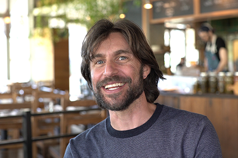 bearded smiling man sitting in cafe