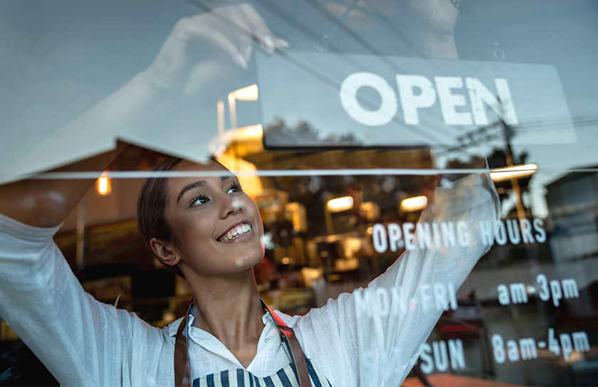 happy woman changing shop sign to open