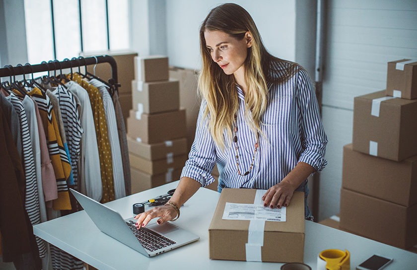 woman in a clothing store on computer with packages