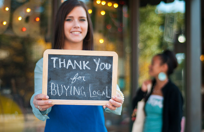 woman holding chalk board that says thank you for buying local