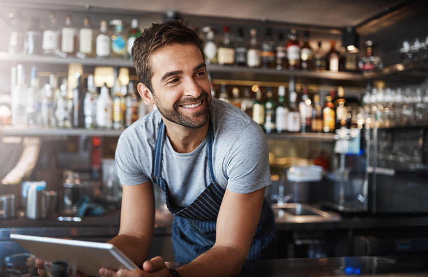 smiling bearded man working in cafe