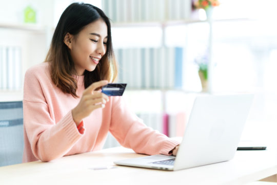 woman holding credit card sitting at table