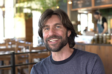 bearded smiling man sitting in cafe