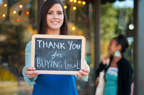 woman holding a sign that says thank you for buying local