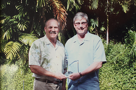 two proud men holding award outside